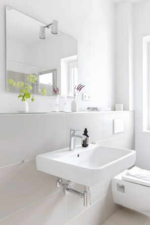 Une salle de bain moderne avec un lavabo blanc, un miroir et des toilettes.