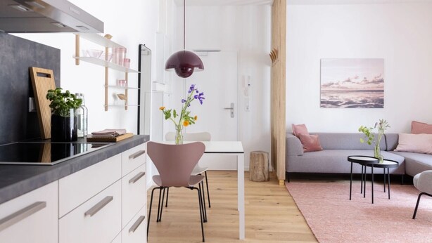A modern kitchen with white cabinets, a black countertop, and a pendant light.