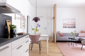 Una cocina moderna con armarios blancos, encimera negra y una lámpara colgante.