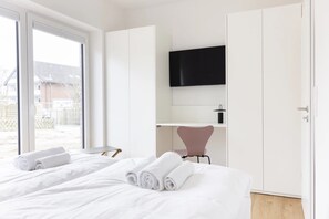Une chambre d’hôtel équipée d’un lit, d’un bureau, d’une chaise, d’une télévision et d’une porte coulissante.