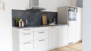A modern kitchen with white cabinets, a black countertop, and a built-in oven. - Apartment 'Backbord' with Balcony and Wi-Fi (Sankt Peter-Ording)