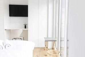 A modern bedroom with a bed, a chair, a TV, and a window with a view. - Apartment 'Backbord' with Balcony and Wi-Fi (Sankt Peter-Ording)