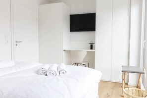 Een hotelkamer met een bed, een televisie aan de muur, een stoel en een klein tafeltje.
