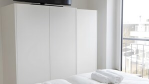 Hotellihuone, jossa on kaksi sänkyä, seinälle asennettu taulutelevisio sänkyjen yläpuolella ja suuri ikkuna, josta avautuu näkymä kaupunkiin.