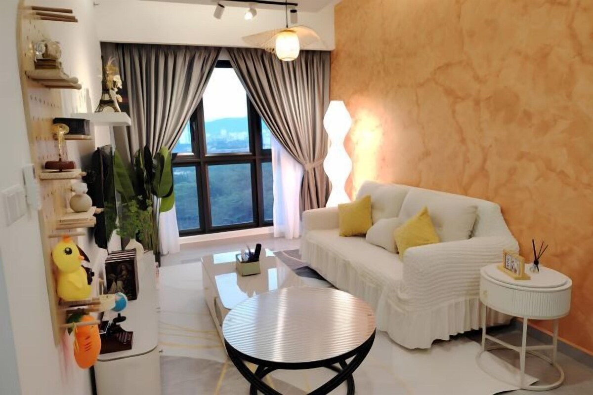A modern living room with a white sofa, a round coffee table, and a view through large windows.