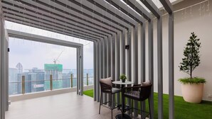 A modern interior with a balcony, a round table with chairs, and a potted plant. - Agile Residence Dual-Key Gem @ Bukit Bintang F16 By Natol (Kuala Lumpur)