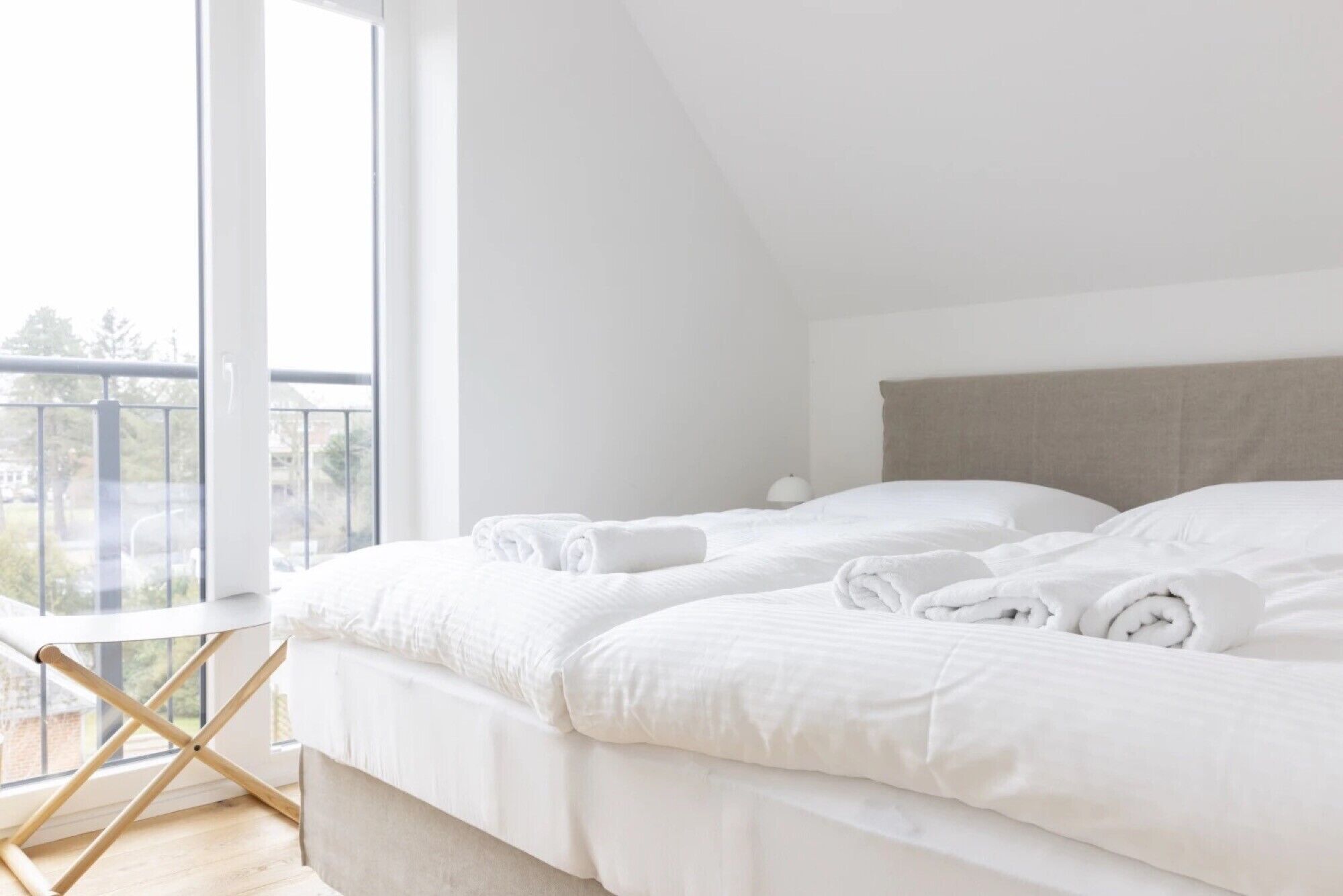 Een slaapkamer met twee bedden, een balkon en uitzicht.