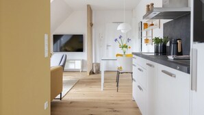 Une cuisine moderne avec des armoires blanches, un comptoir noir et une hotte de cuisinière en acier inoxydable.