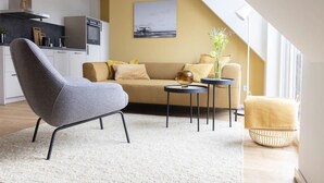 Un salon moderne avec un canapé, un fauteuil et de petites tables rondes.