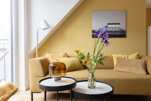 Ein modernes Wohnzimmer mit einer Couch, einem runden Couchtisch, einer Vase mit Blumen und einer Lampe.