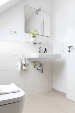 A modern bathroom with a white sink, mirror, and toilet.