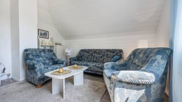 Ein Wohnzimmer mit zwei gemusterten Sofas, einem weißen Couchtisch und einem weißen Ventilator.