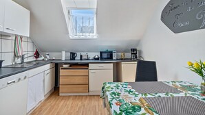 A compact kitchen with a window, a microwave, a coffee maker, and a dining area with a table.