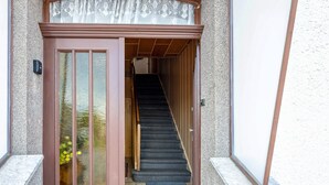 A staircase leading to an upper floor, a door with a glass panel, and a small mat at the bottom.