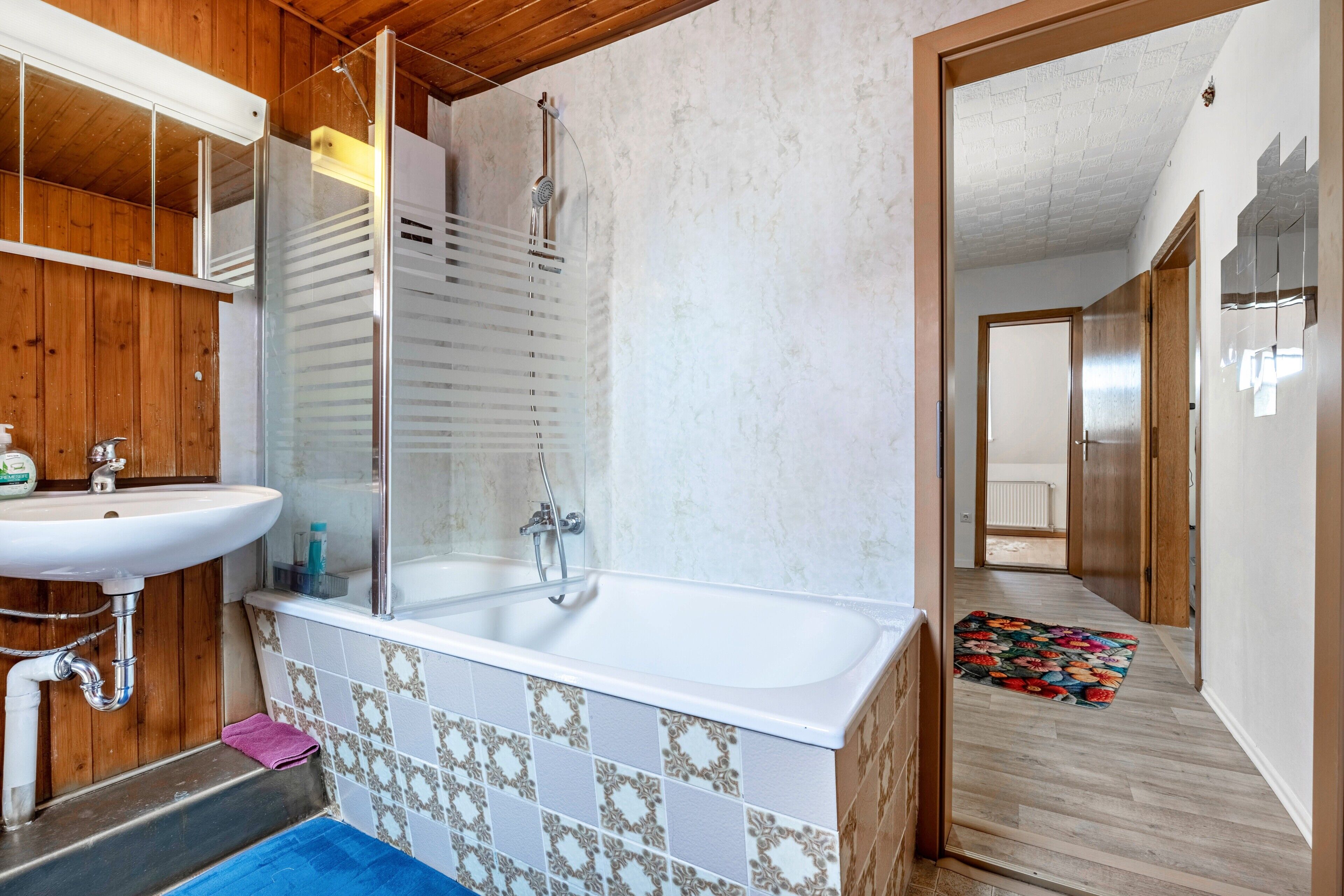 A bathroom with a bathtub, a sink, and a shower enclosure.
