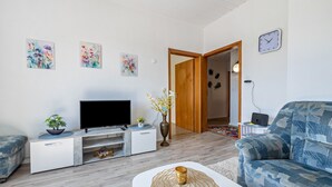 A living room with a flat-screen TV, a sofa, a coffee table, and artwork on the wall.