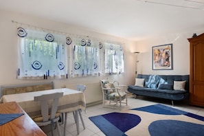 A dining area with a table and chairs, a sofa, a patterned rug, and a radiator.