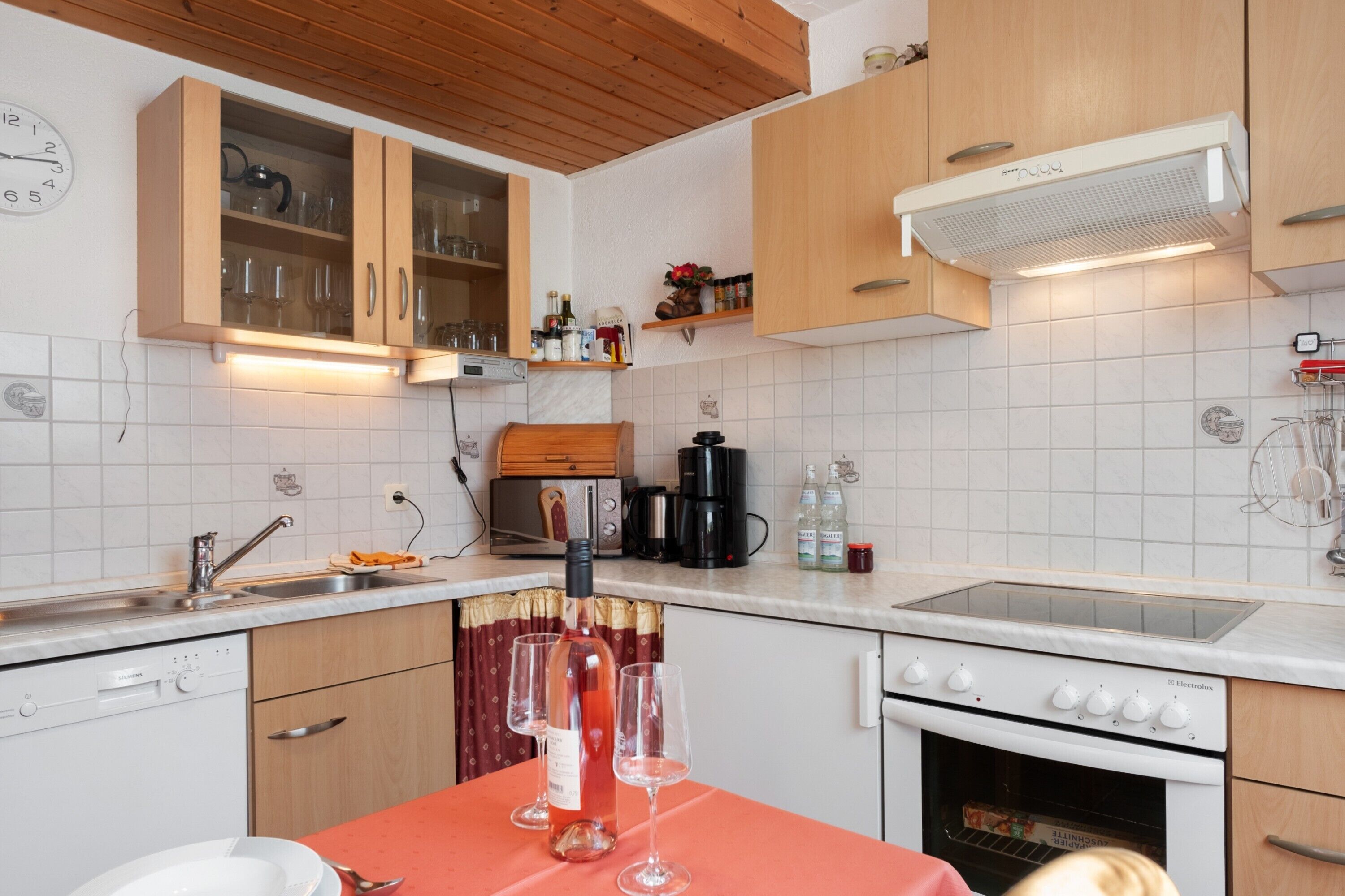 Une cuisine avec des meubles de rangement en bois, un four encastré, un four à micro-ondes et une machine à café.