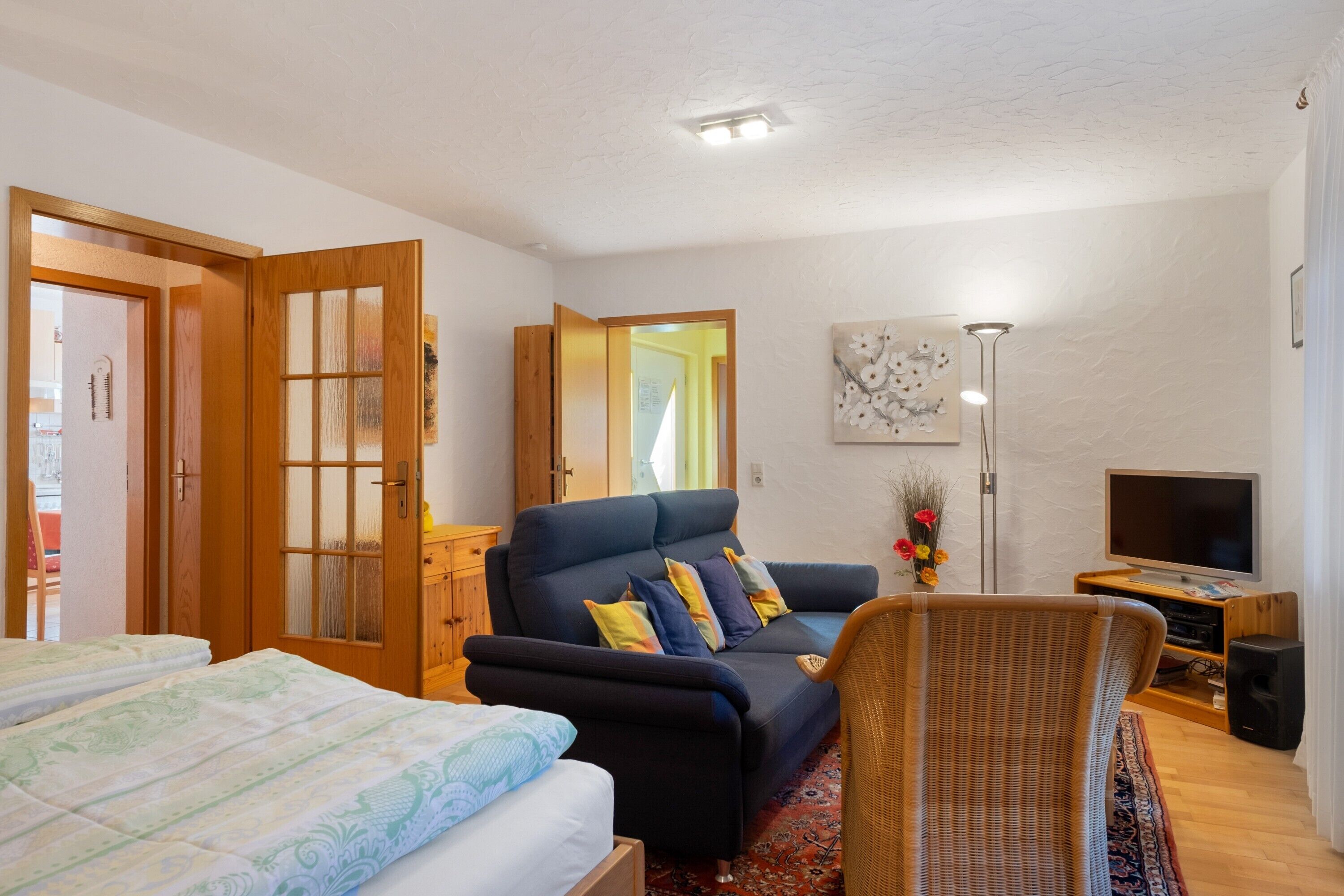 A room with a sofa, a chair, a TV, and a bed.