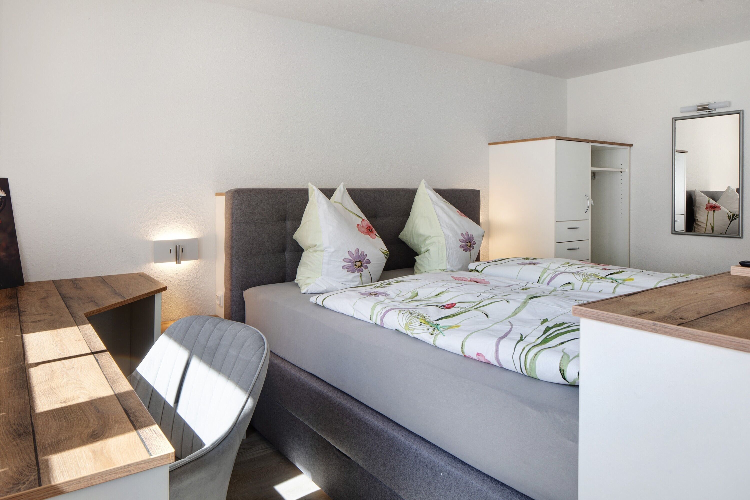 Une chambre à coucher comprenant un lit, une table de chevet, une armoire et un miroir.