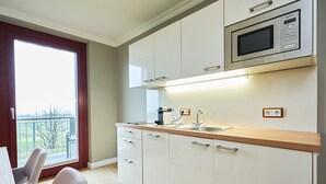 A modern kitchen with white cabinets, a stainless steel sink, and a built-in microwave.