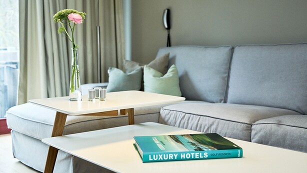 A modern living room with a sofa, a coffee table, and a book titled "Luxury Hotels Golf Resorts".