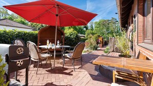 A patio with a grill, chairs, a table, and a red umbrella. - Holiday Home 'Ankerglück' with Private Terrace and Wi-Fi (Lensahn)