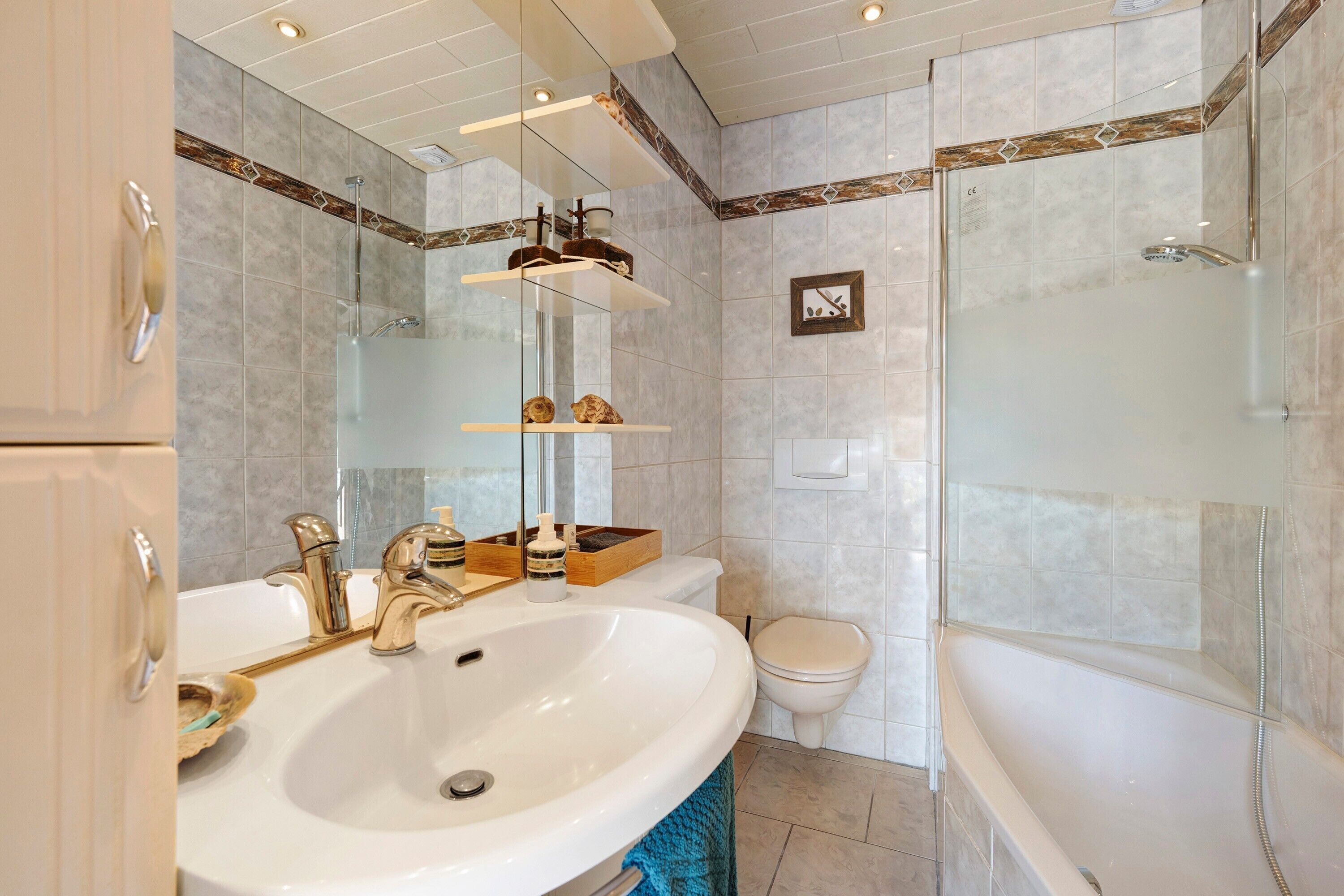 A modern bathroom with a large sink, toilet, and glass-enclosed shower.
