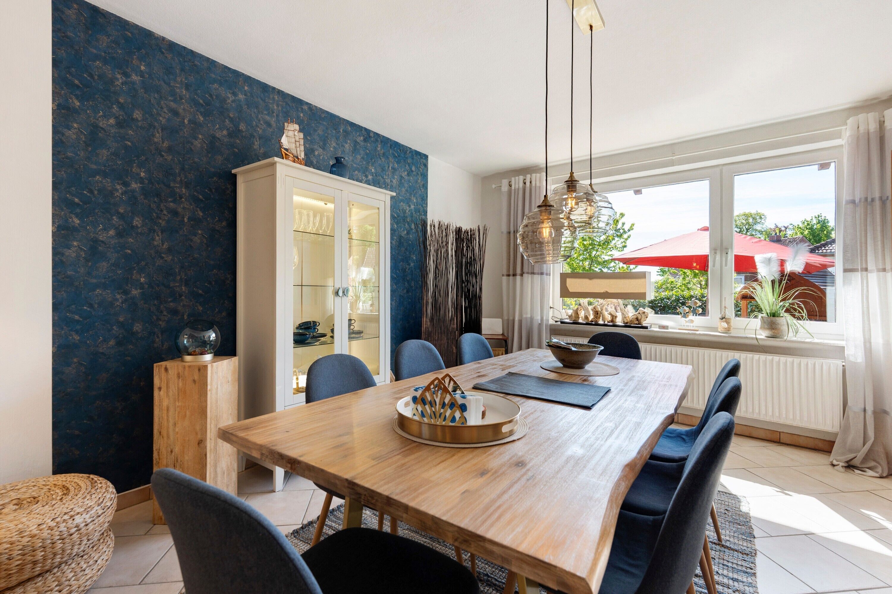 A dining area with a wooden table, chairs, a cabinet, and a view of the outdoors.