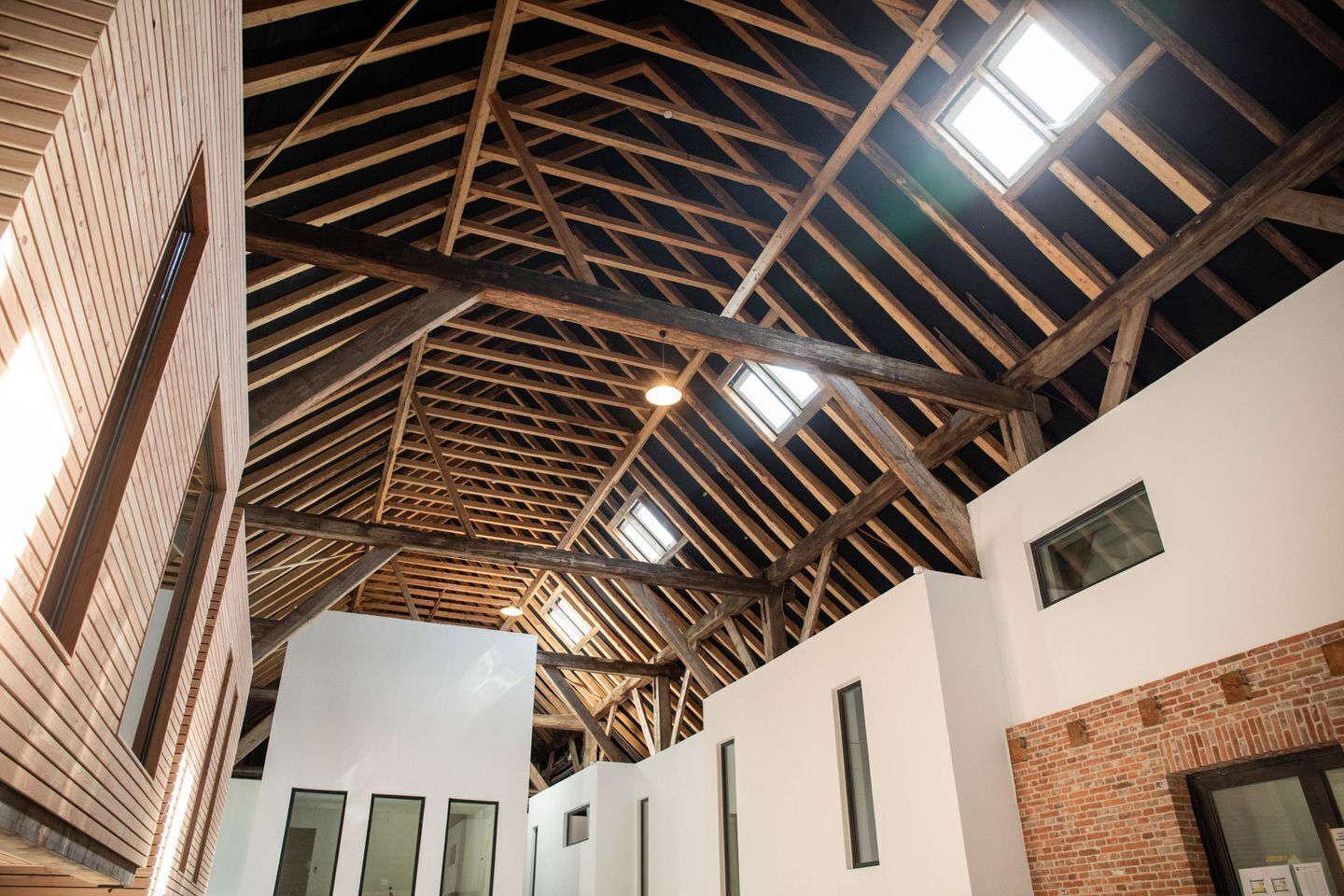 Een gebouw met een hoog houten plafond, meerdere ramen en een bakstenen muur.