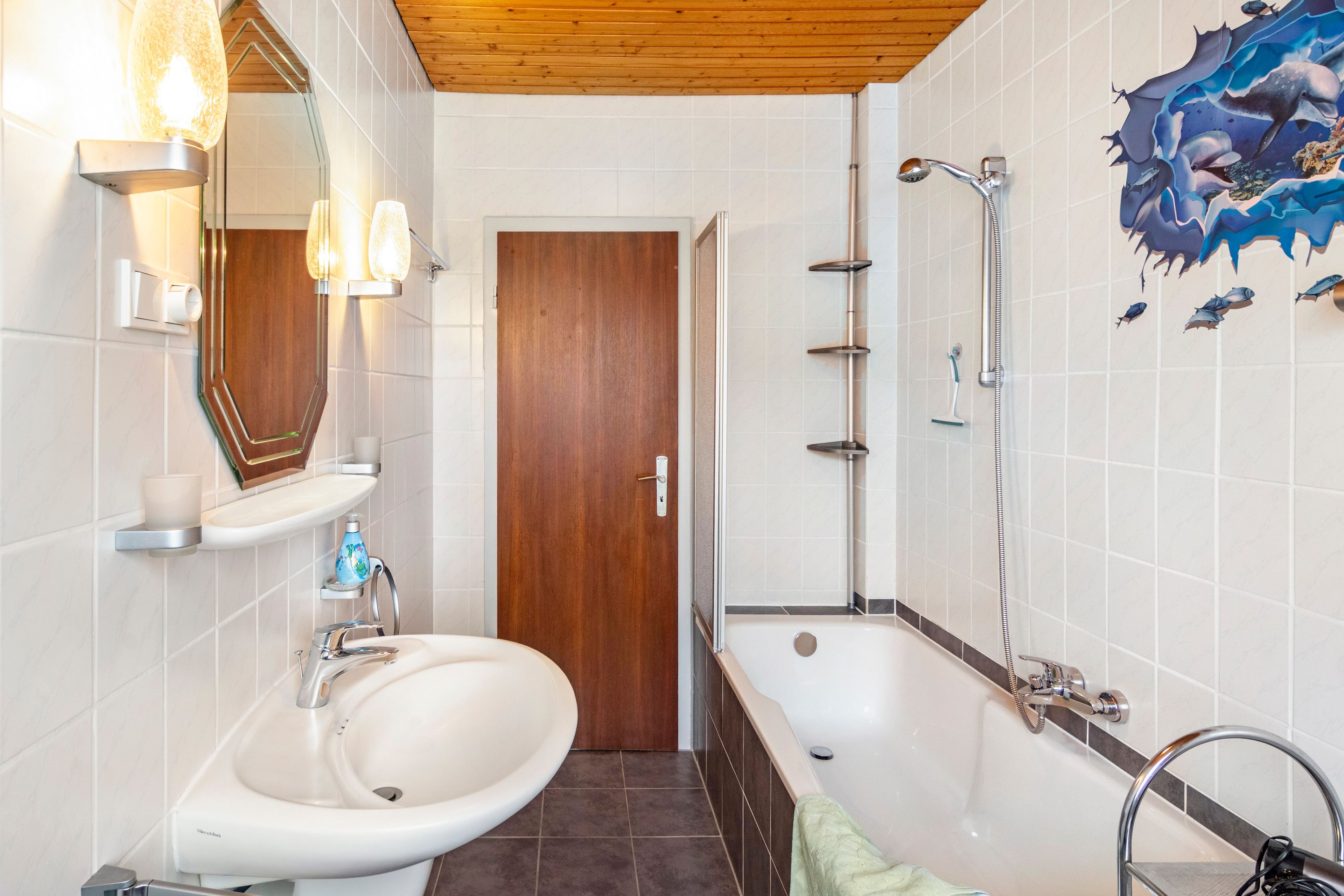 Ein Badezimmer mit Waschbecken, Spiegel, Dusche und Wanddekoration.