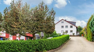 Een pad dat leidt naar een wit gebouw met veel ramen en een rood dak.