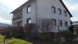 A two-story building with a flat roof, multiple windows, and a visible balcony on the upper floor. - Apartment 'Wolfswind' with Mountain View, Balcony and Wi-Fi (Langelsheim)