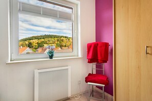 A bathroom with a window, a radiator, a towel rack, and a view of a forested hill. - Apartment 'Wolfswind' with Mountain View, Balcony and Wi-Fi (Langelsheim)