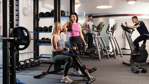 Een sportschool met gewichthefapparatuur, loopbanden en dumbbells.