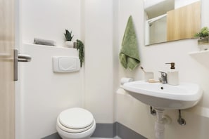 Casa de banho moderna com sanita, lavatório e espelho.