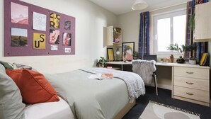 Een slaapkamer met een bed, een bureau en een raam.
