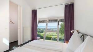 A bedroom with a large bed, a view of a landscape, and a window with curtains. - Apartment '4' with Lake View, Private Terrace and Wi-Fi (Kressbronn am Bodensee)
