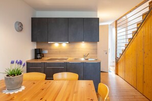 Una cucina moderna con mobili scuri, un tavolo da pranzo in legno e una pianta in vaso.