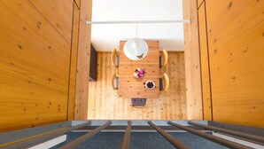 A wooden-paneled room with a table and chairs, a hanging light fixture, and a view through a window. - Apartment '1' with Lake View, Private Terrace and Wi-Fi (Kressbronn am Bodensee)