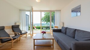 A modern living room with a sofa, two chairs, a table, and a view through large glass doors. - Apartment '1' with Lake View, Private Terrace and Wi-Fi (Kressbronn am Bodensee)