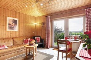 A wooden interior with a sofa, a table, and a chair. - Apartment 'Morgensonne' with Mountain View, Private Terrace and Wi-Fi (Höchenschwand)