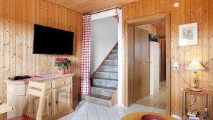 En inredning med träpanel, TV, skrivbord, stol, trappa och en lampa.