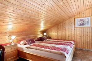 A wooden-paneled room with a bed, bedside tables, and a framed picture on the wall. - Apartment 'Morgensonne' with Mountain View, Private Terrace and Wi-Fi (Höchenschwand)