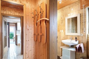A wooden interior with a wooden door, a white sink, and a mirror above it. - Apartment 'Morgensonne' with Mountain View, Private Terrace and Wi-Fi (Höchenschwand)