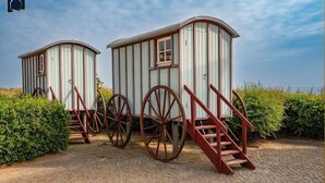 Deux petits bâtiments en bois, équipés de grandes roues et d’escaliers en bois.