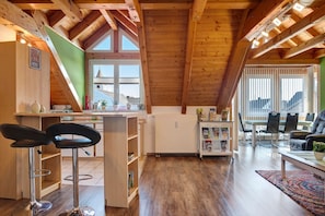 Una habitación con techos altos, vigas de madera, una zona de cocina, una barra y un área de estar con vistas.