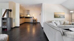 En moderne stue med sofa, spiseplads og et køkken med komfur.