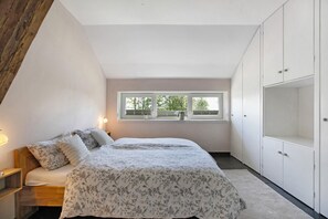 A bedroom with a bed, a window, and a wardrobe.