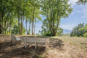 Un banc dans un parc, entouré d’arbres, avec vue sur la mer.